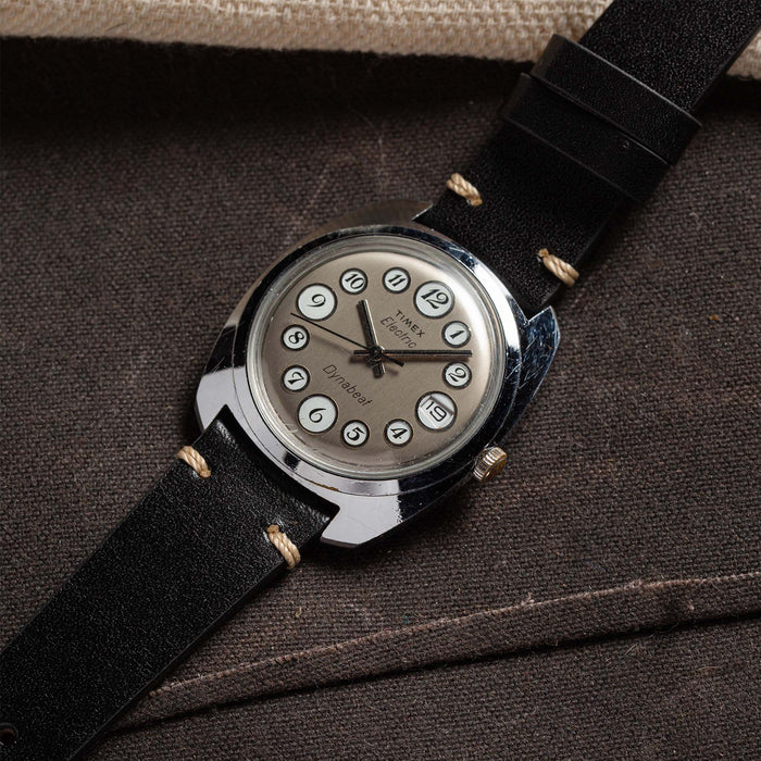 flatlay of 1975 Timex Electric Dynabeat "Rotary" against against a brown background