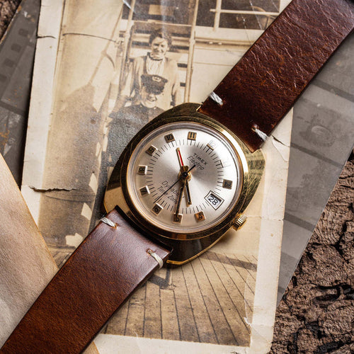 flatlay of the 1975 Timex Electric Dynabeat Time Zone, on a background of vintage photos