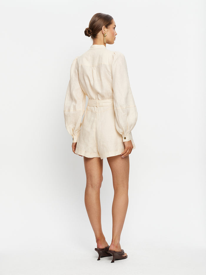 Woman wearing a cream-colored dress with a belt on a white background