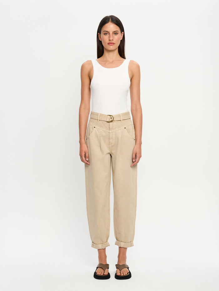 Woman wearing a white tank top and beige denim jeans on a white background