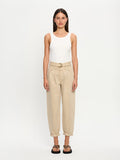 Woman wearing a white tank top and beige denim jeans on a white background