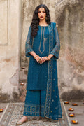 Woman in a blue traditional outfit standing against a textured wall.