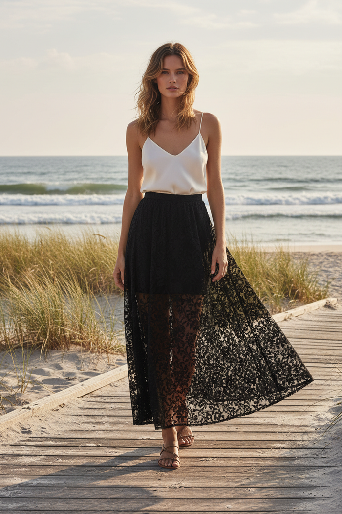 Black sheer floral lace maxi skirt styled over a simple black layer on a beach boardwalk
