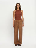 Woman wearing a rust-colored sleeveless top and brown wide-leg pants on a white background