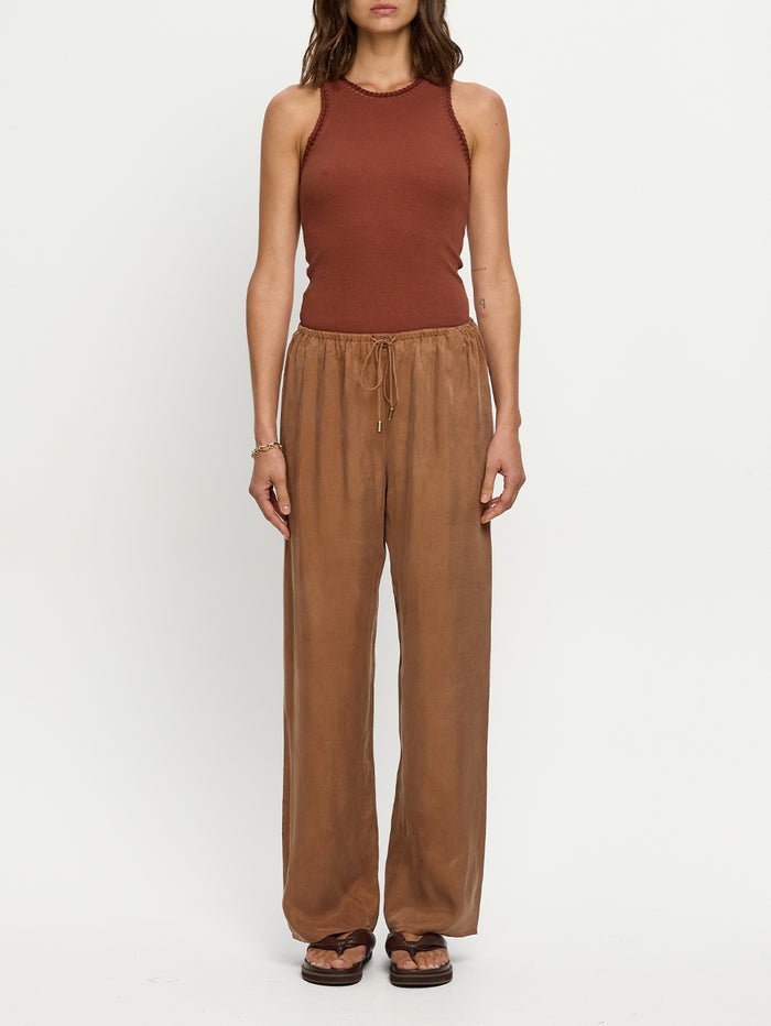 Woman wearing a brown sleeveless top and wide-leg pants on a white background