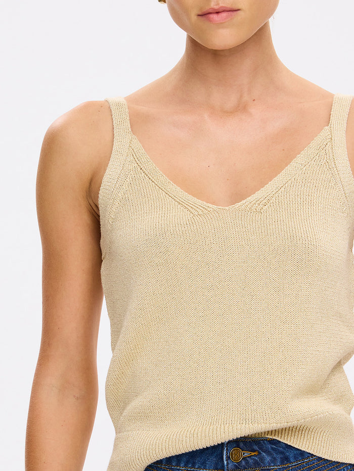Beige knitted tank top worn by a person on a plain background
