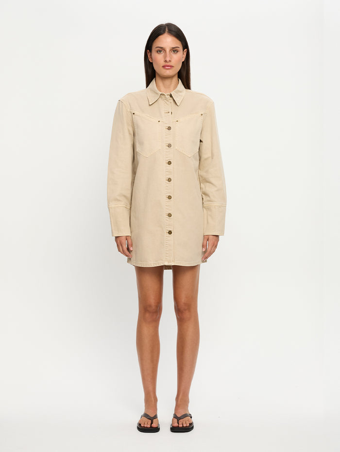 Woman wearing a beige dress with buttons on a white background