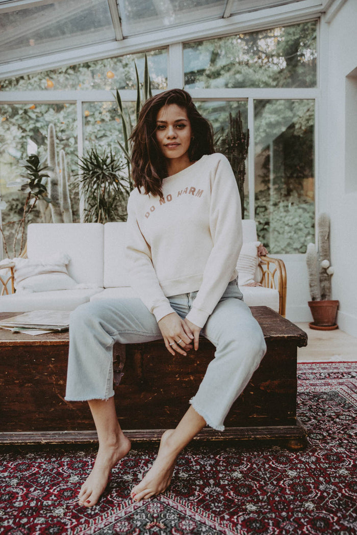 Woman sat on coffee table wearing Tapioca Do No Harm But Take No Shit Sweatshirt by The Bee and The Fox