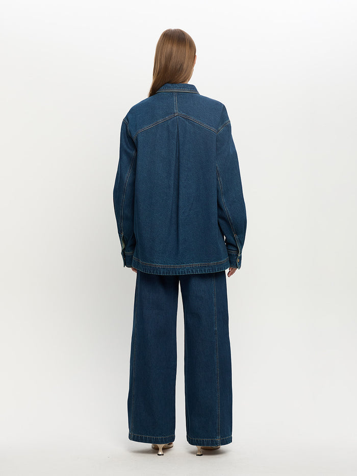 Person wearing a blue denim jacket and pants on a white background