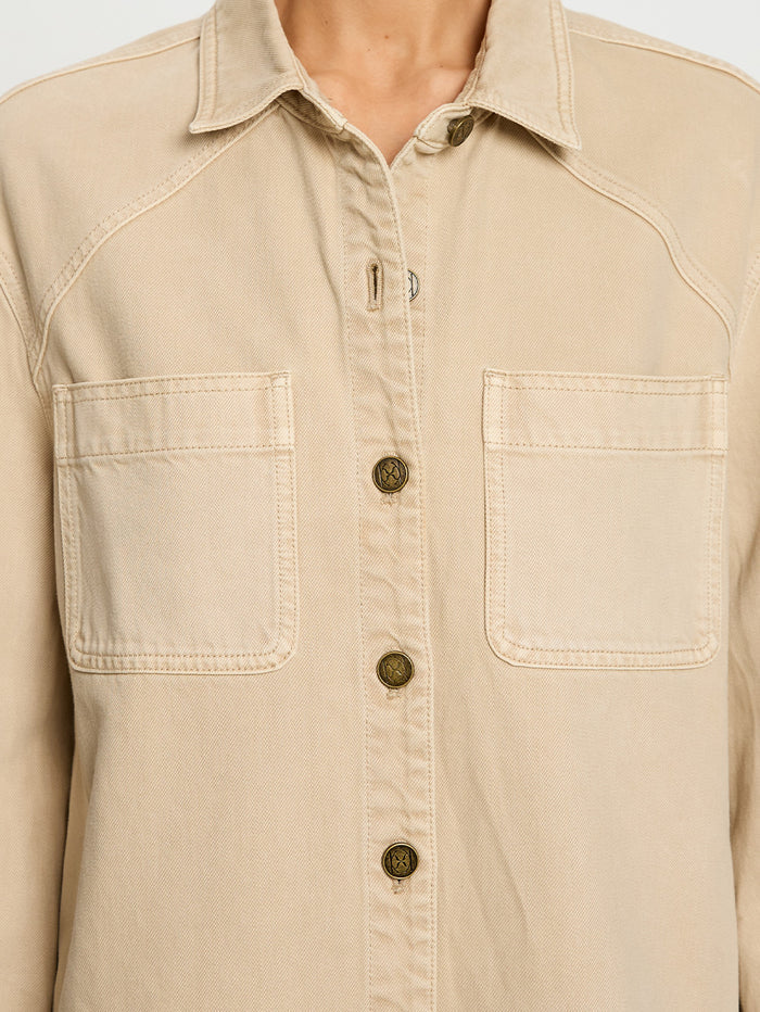 Beige button-up shirt with two front pockets on a plain background