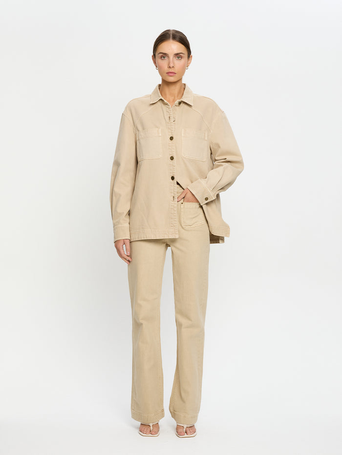 Woman wearing a beige denim shirt and jeans on a white background