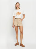 Woman wearing a white t-shirt with a logo and beige shorts on a white background