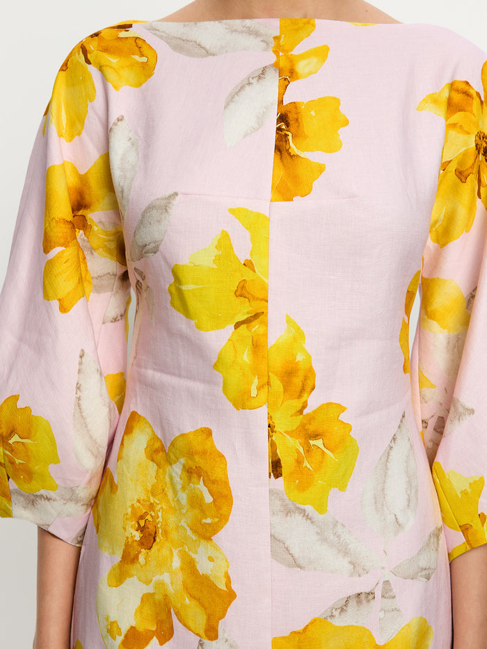 Close-up of a garment with yellow floral pattern on a light pink background