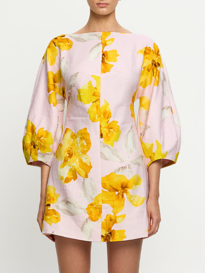 Woman wearing a pink dress with yellow floral pattern on a white background