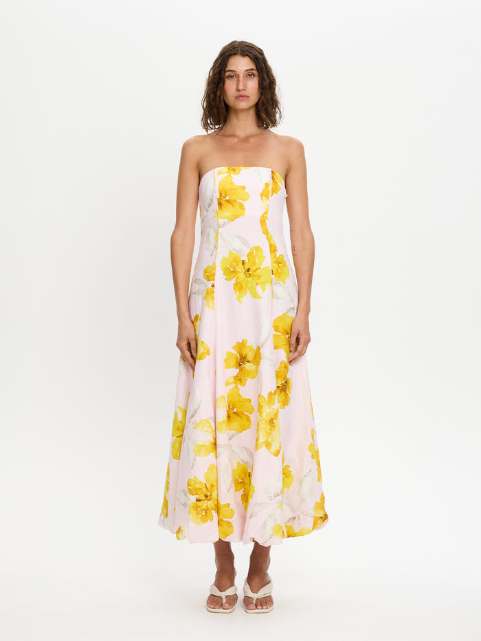 Woman wearing a strapless dress with yellow floral pattern on a white background