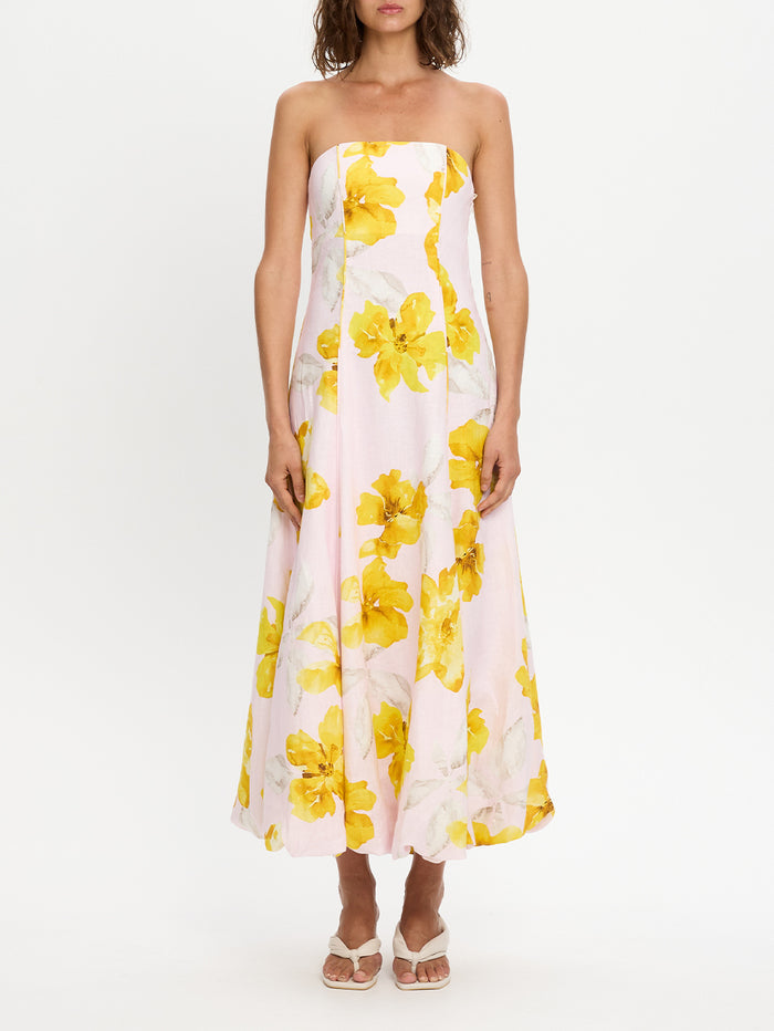 Woman wearing a strapless dress with yellow floral pattern on a white background