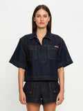 Woman wearing a dark denim outfit on a white background
