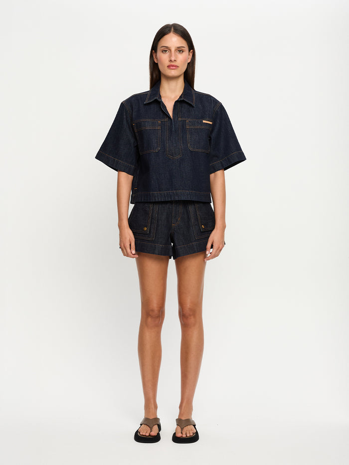 Woman wearing a dark denim outfit on a white background