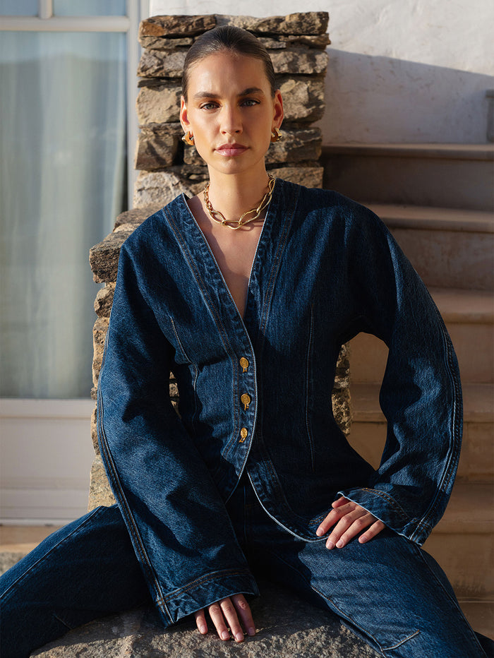Person wearing a blue denim outfit sitting on stone steps.