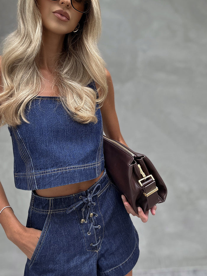Woman wearing a denim outfit holding a brown bag.