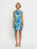 Woman wearing a green dress with blue floral pattern on a white background