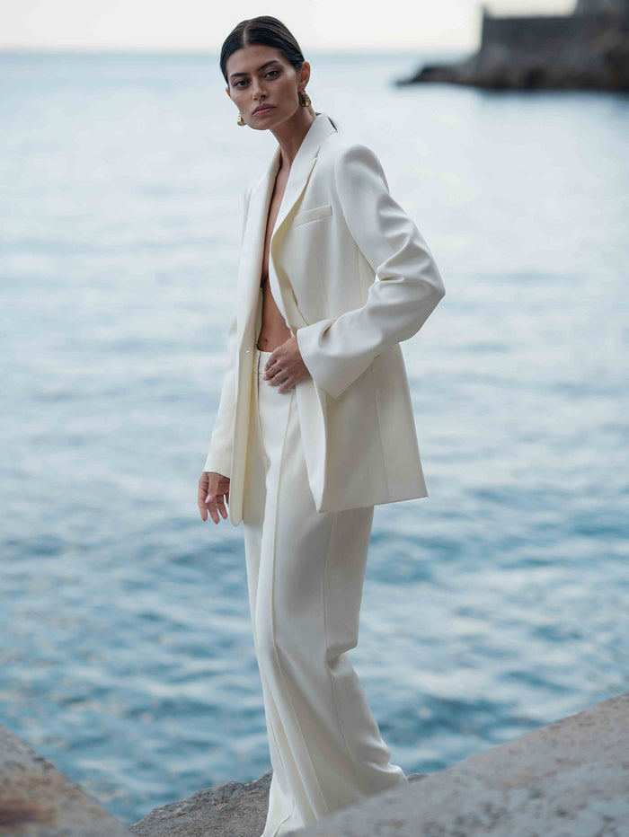 Woman in a white suit standing by the water