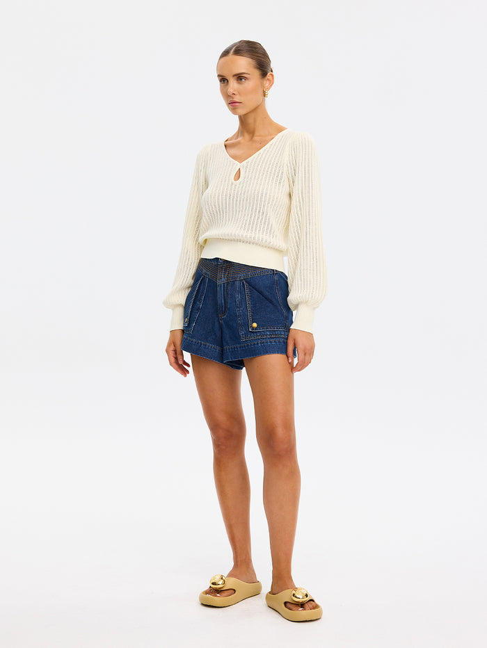 Woman wearing a white sweater and blue denim shorts on a white background