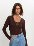 Woman wearing a brown long-sleeve top with lace-up front and blue jeans on a white background