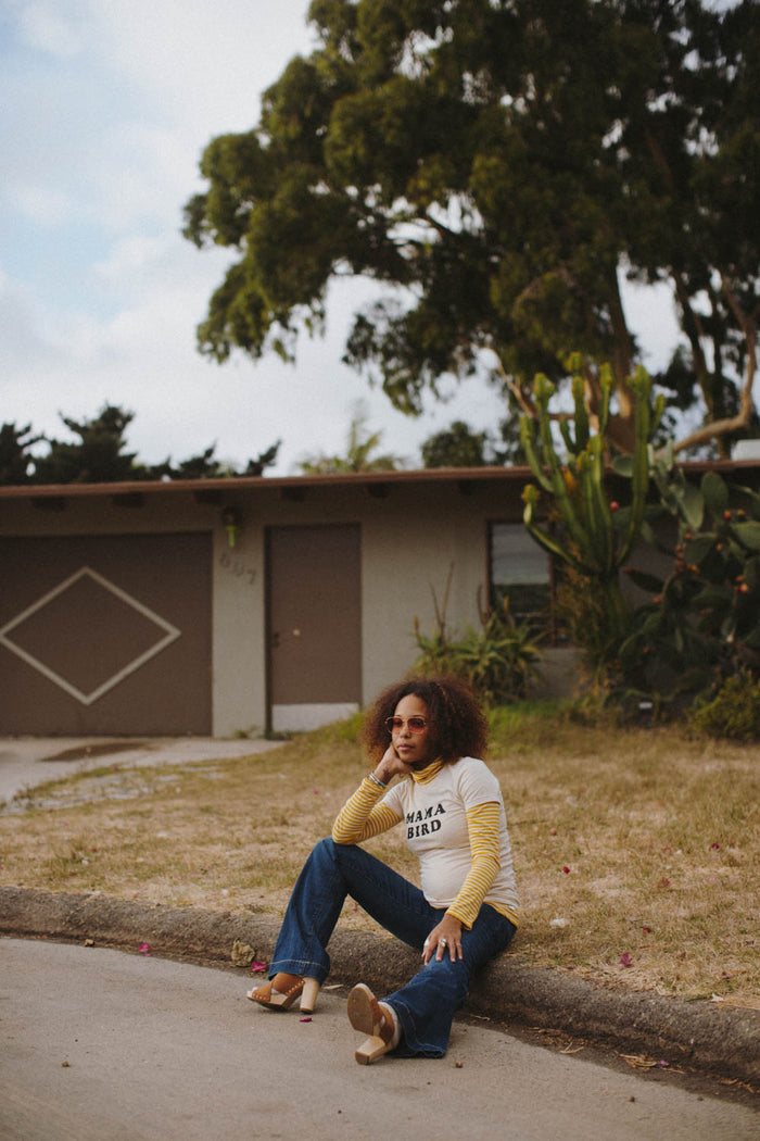 Woman sitting on curb in the Mama Bird shirt by The Bee & The Fox