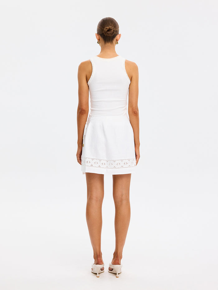 Woman wearing a white dress with lace details on a white background