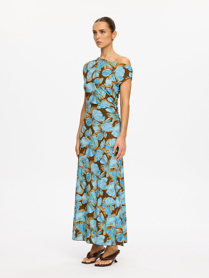 KIVARI Nieve Jersey Maxi Dress in Blue - side view of model wearing blue and brown floral one-shoulder jersey maxi dress