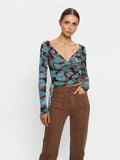 KIVARI Nieve Mesh Top in Blue Floral Print – three-quarter view showing drawstring hem, model wearing women's long-sleeve wrap mesh top with brown pants
