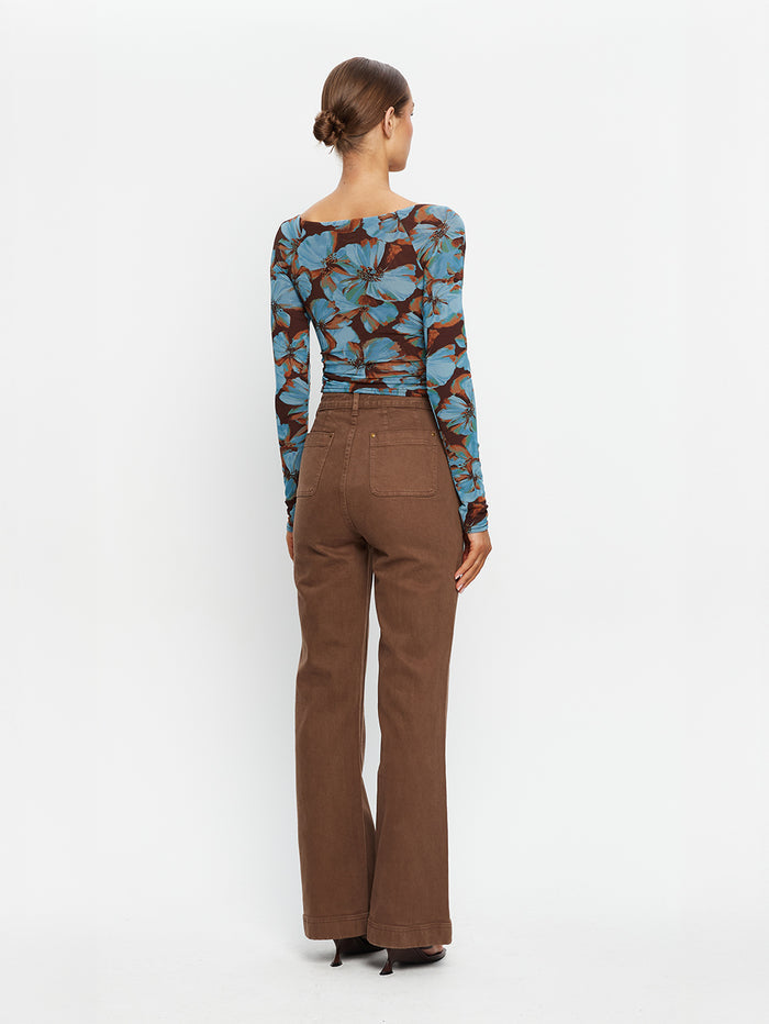 KIVARI Nieve Mesh Top in Blue Floral Print – back view of model wearing women's long-sleeve wrap mesh top with brown flare pants