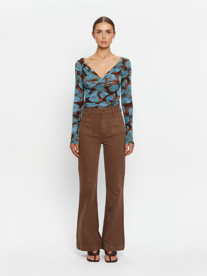 KIVARI Nieve Mesh Top in Blue Floral Print – full-length front view of model wearing women's long-sleeve wrap mesh top with brown flare pants