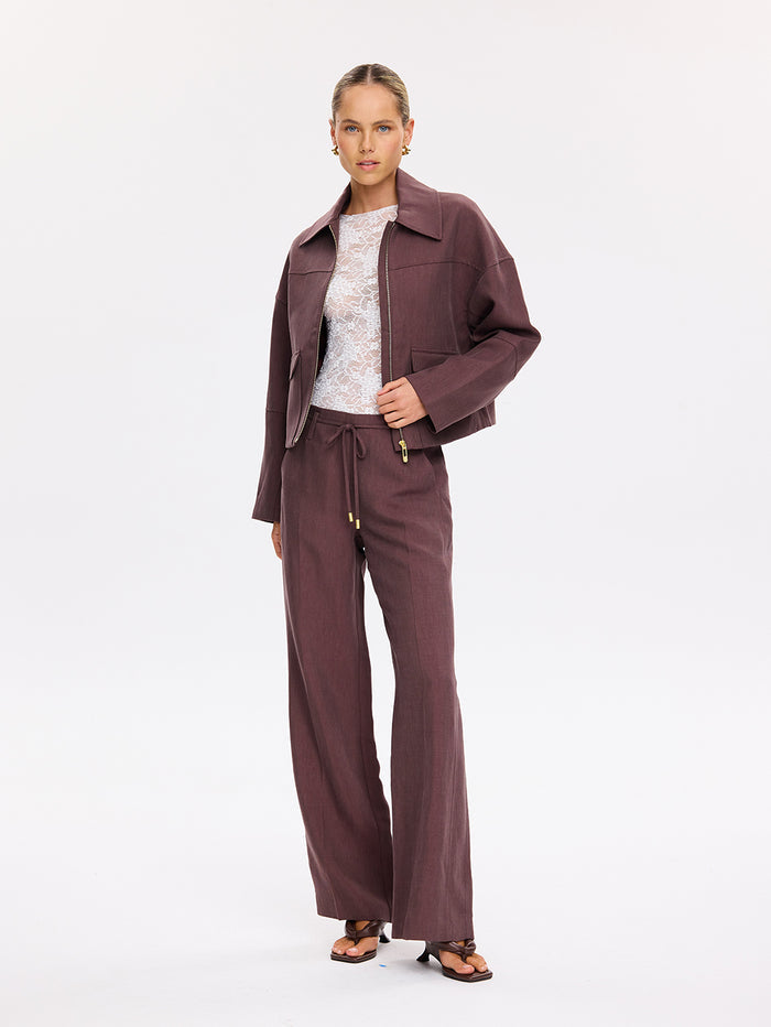 KIVARI Nyah Jacket in Plum - woman wearing plum zip jacket with matching wide-leg pants and lace top, model photo