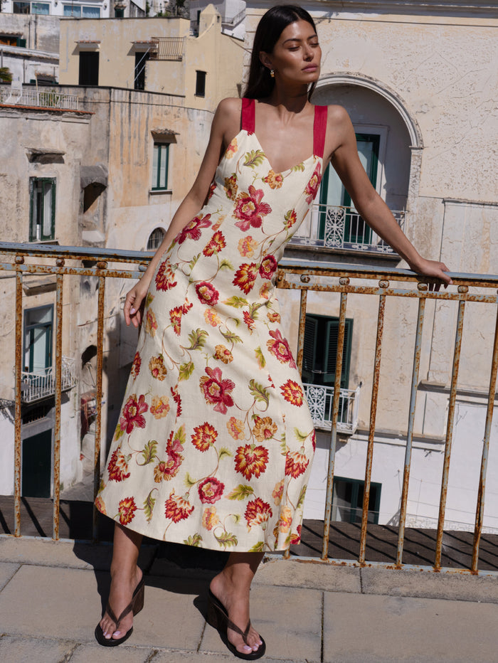Woman in a floral dress standing on a balcony with a cityscape background