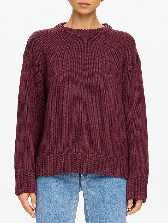 KIVARI Odette Crew Neck Jumper in Plum – close-up torso detail of women's dark plum ribbed knit crew neck sweater showing ribbed hem and sleeve cuffs with blue jeans