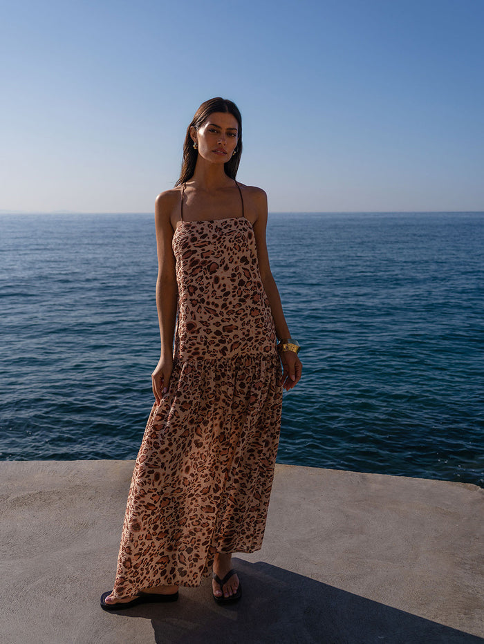 Woman in a leopard print dress standing by the ocean
