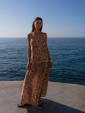 Woman in a leopard print dress standing by the ocean