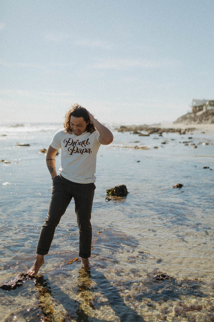 Man standing in the sea wearing Proud Papa Shirt for Men by The Bee and The Fox