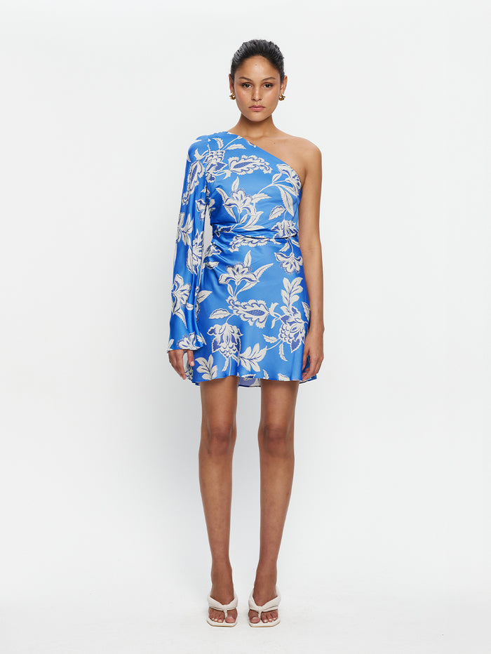 Woman wearing a blue floral one-shoulder dress on a white background