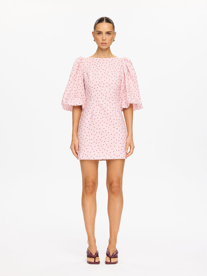 Woman wearing a pink polka dot dress on a white background