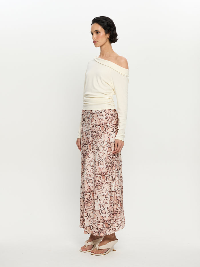 Woman wearing a white off-shoulder top and patterned skirt on a white background