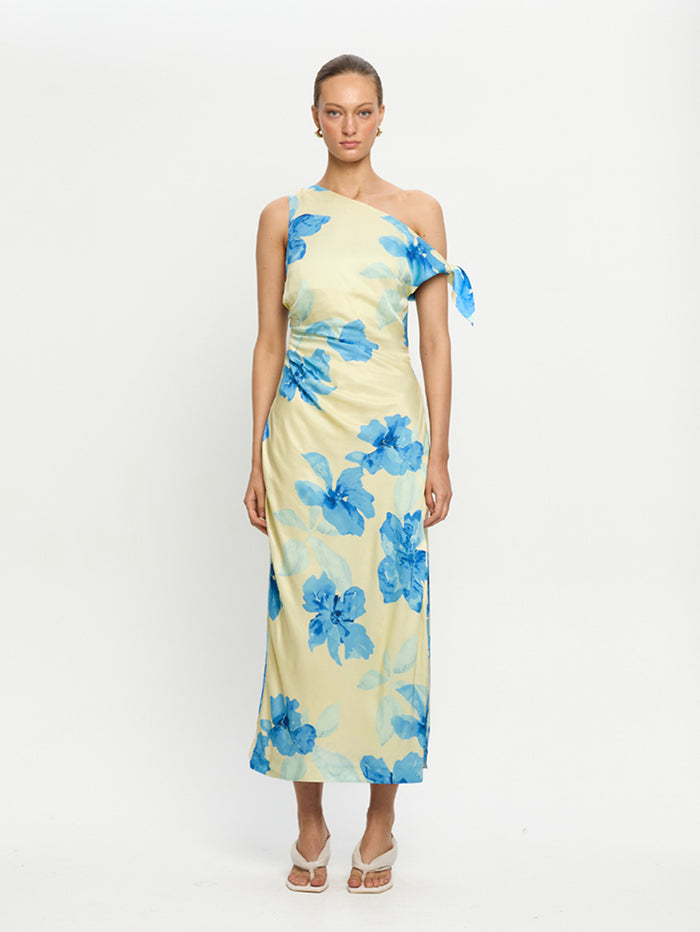 Woman wearing a one-shoulder dress with blue floral pattern on a white background
