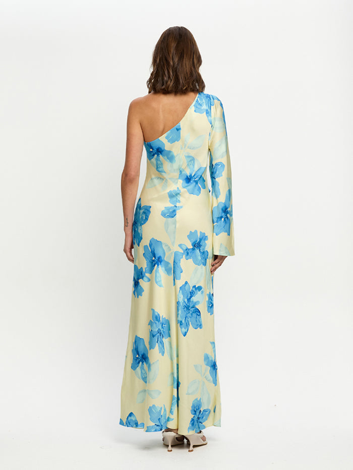 Woman wearing a one-shoulder floral dress with blue flowers on a white background