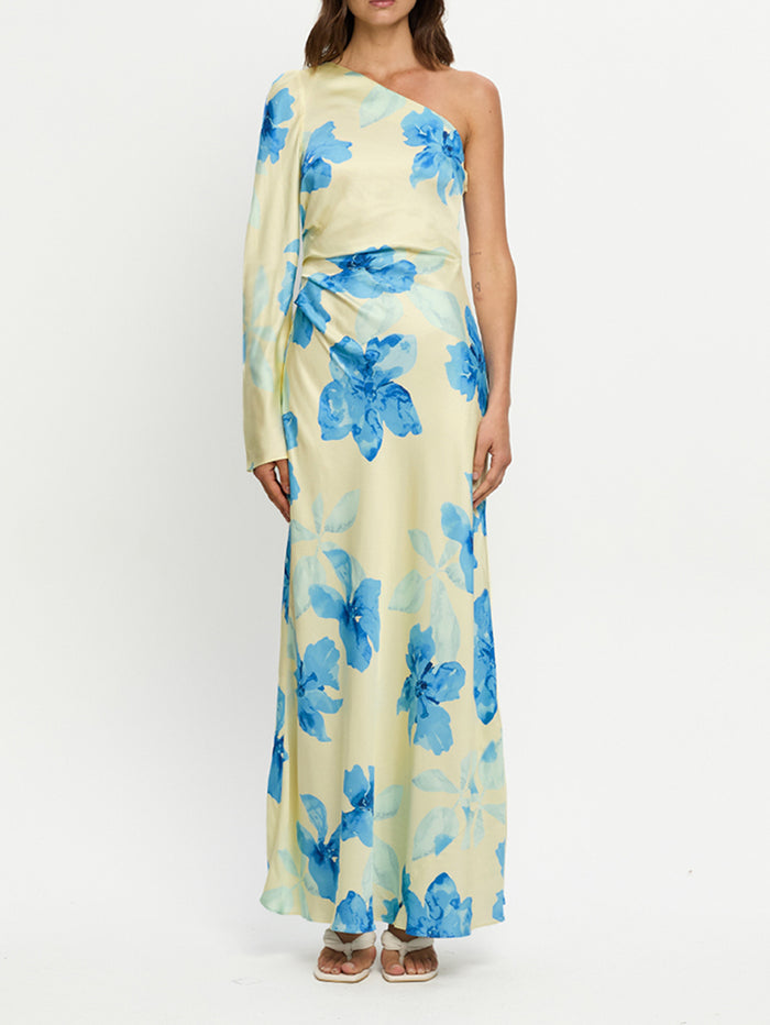 Woman wearing a one-shoulder dress with blue floral pattern on a white background