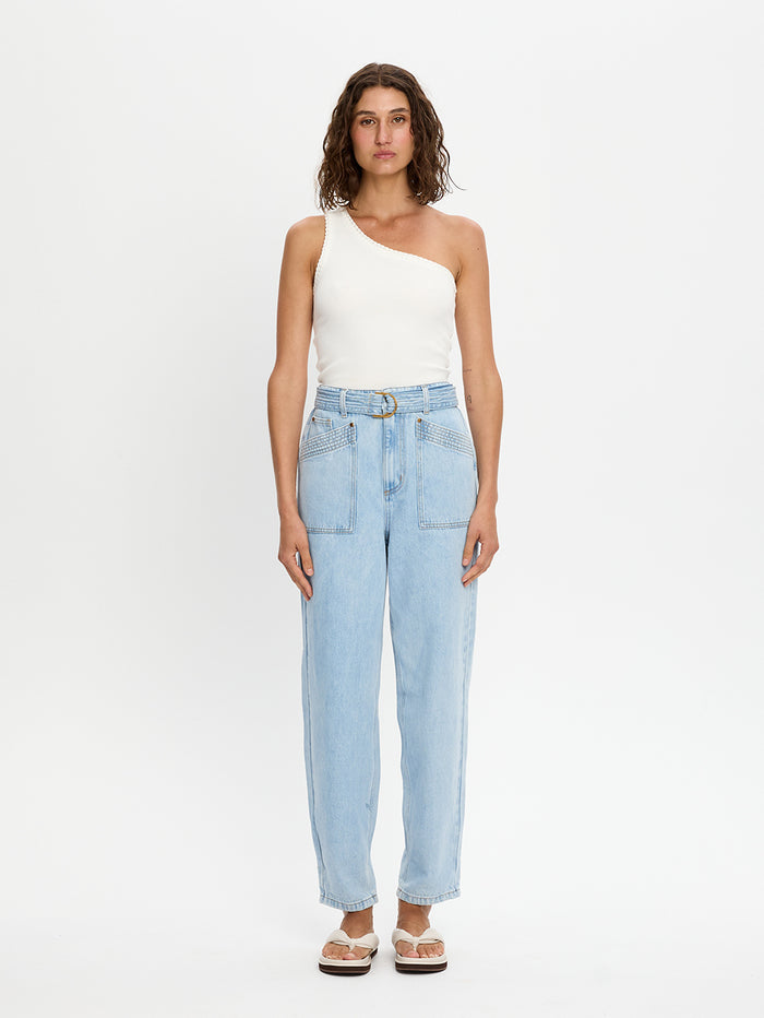 Woman wearing light blue jeans and a white top on a white background