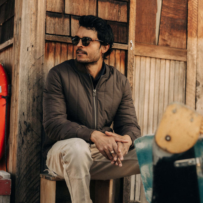 fit model sitting wearing The Able Jacket in Soil Quilted Nylon