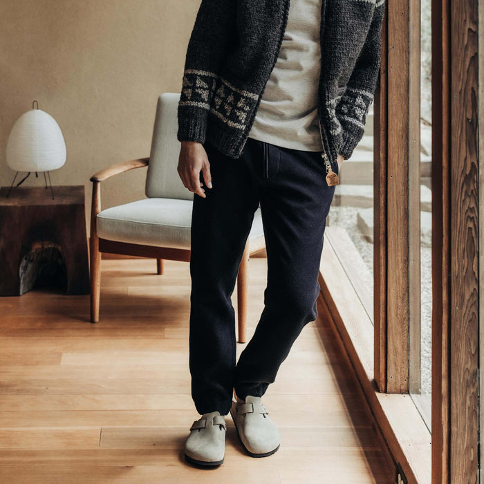 fit model leaning against the wall in The Apres Pant in Coal Waffle