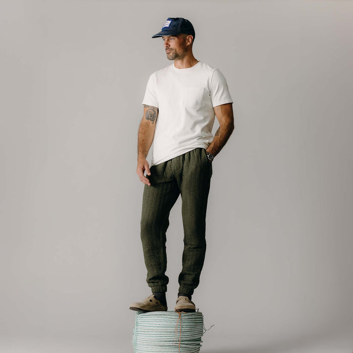 fit model standing on rope wearing The Quilted Apres Pant in Heather Fatigue Olive Jersey